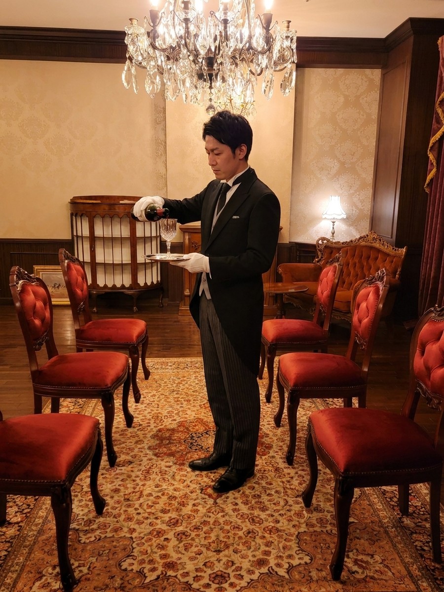 サロンで給仕するプロフェッショナル認定の執事